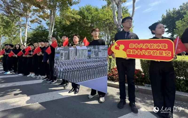 沈陽市人民廣場上，大學生們手持閱兵的圖片，告慰英烈。人民網記者 周頌雪攝